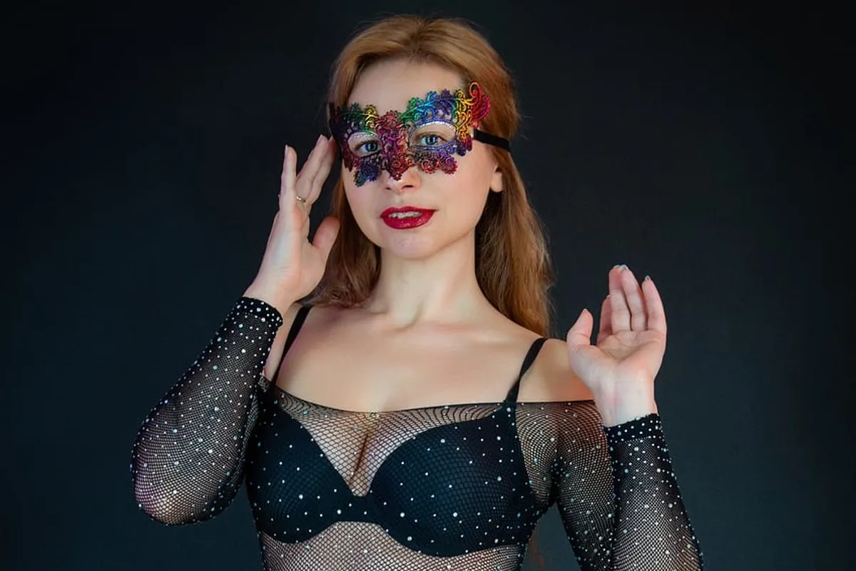 Kvinna med maskeradmask och glittrande nätbody
