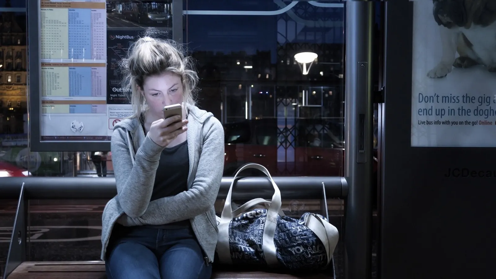 Kvinna som tittar i mobilen en kväll