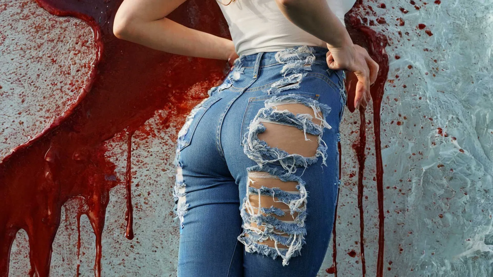 Kvinna i trasiga jeans bakifrån framför en vägg med röd färg